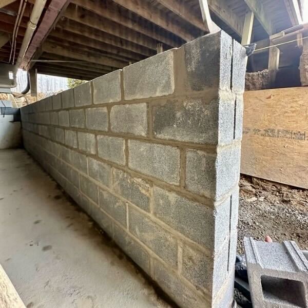 Ongoing foundation wall replacement in Gainesville, FL, showing halfway installation of cinder blocks during new wall construction.