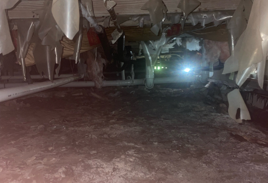 A damp surface with mold, torn vapor barrier, and structural damage before wet crawl space repair in Jacksonville Beach, FL.