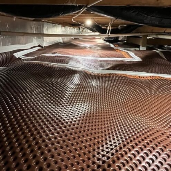 Installed crawl space drainage matting in Jacksonville, FL, directing water to the drainage system for moisture control.