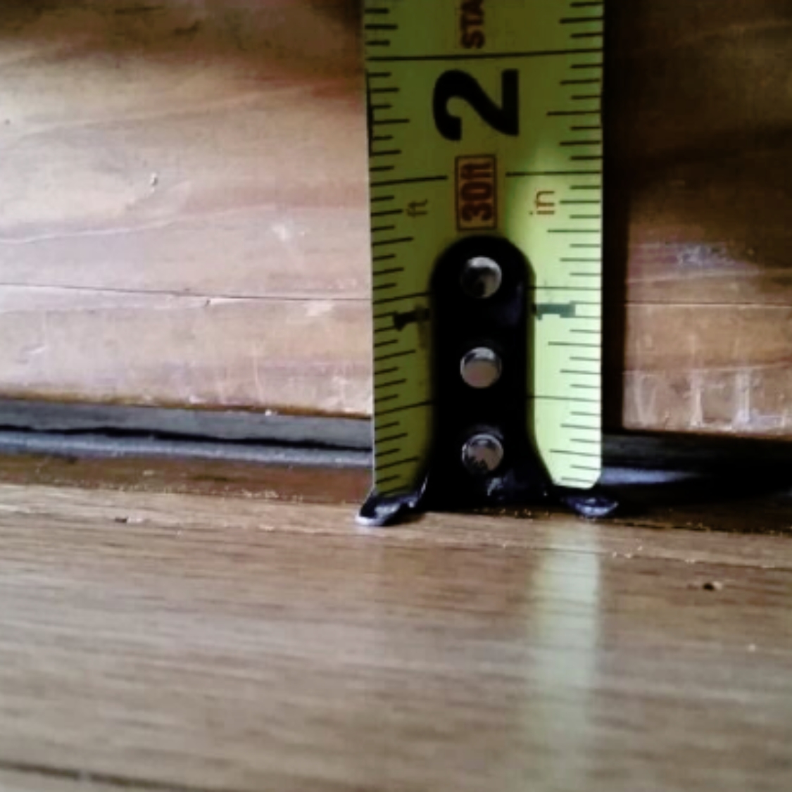 Separation or gap between floor and wall in a Northern Florida home caused by foundation settlement and shifting soils.
