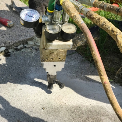 Technician lifting a sunken pool deck using polyurethane foam injection, a pool deck crack repair solution in Lake City, FL.