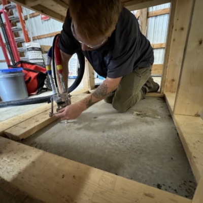 Expert performing polyurethane foam injection to lift sunken concrete slab and level uneven surfaces in Lake City, FL.