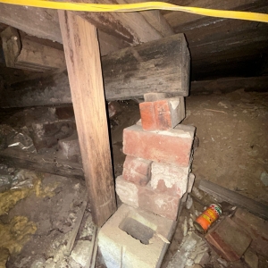 An improvised brick crawl space support stack, showing instability and failing supports, causes an unlevel floor in Palatka, FL.