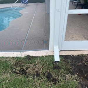 Short downspout near concrete pool deck showing poor drainage, causes of cracks in pool decks in Ocala, FL.