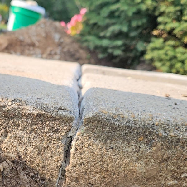 Close-up of cracked and separated concrete walkway caused by soil erosion, needing sidewalk crack repair in Northern Florida.