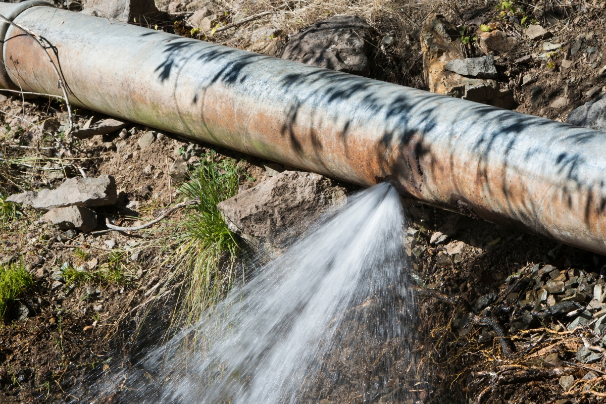 Water spraying from a damaged drainage pipe, showing how broken drainage lines cause a poor drainage system in Palm Coast, FL.