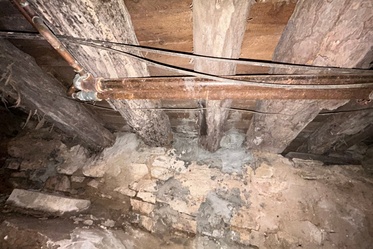 Corroded metal plumbing lines running through the crawl space, an aging pipe causes moisture leaks in St. Augustine, FL.