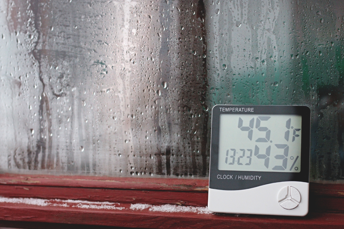 Moisture-covered window with a digital gauge showing high humidity causing condensation in the basement in St. Augustine, FL.