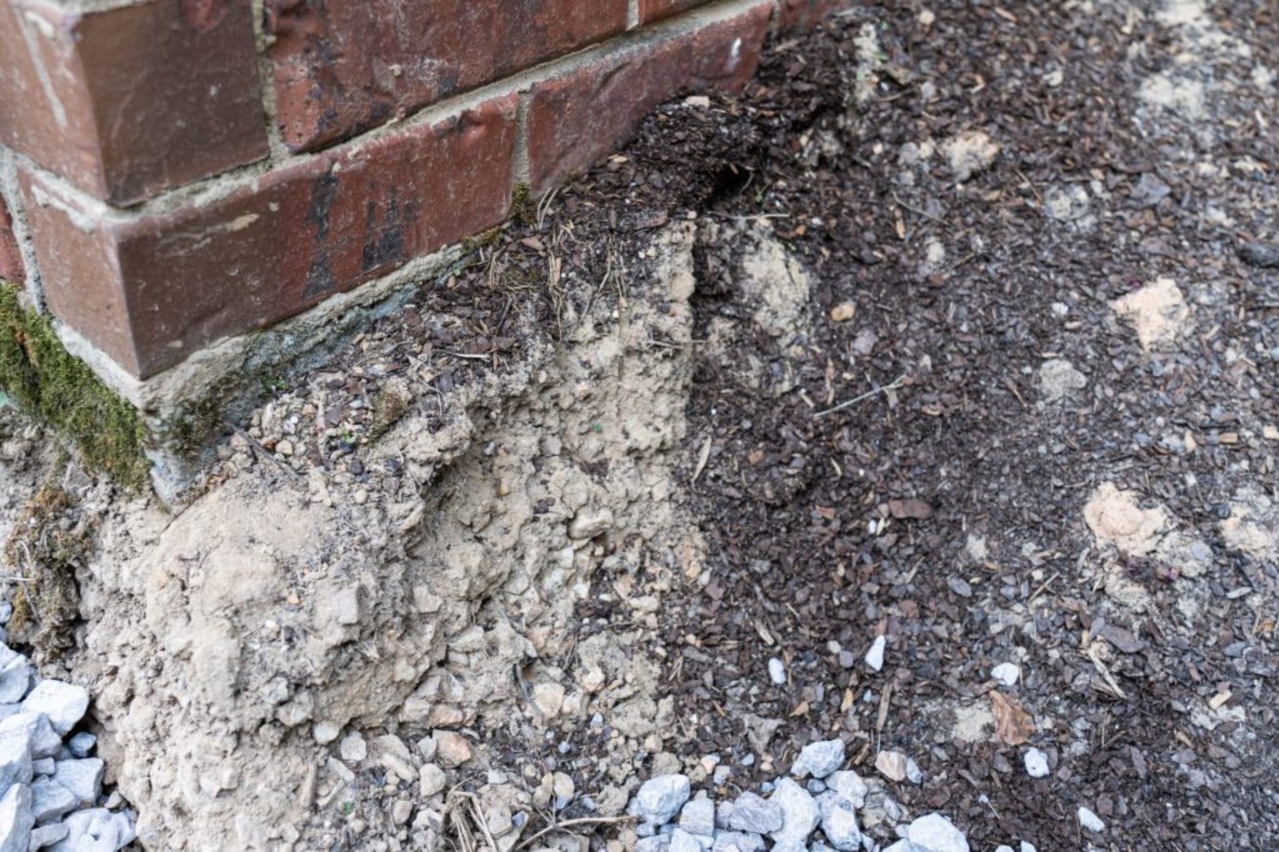 Loose soil eroding around a foundation wall, showing how sandy Florida soil weakens poor foundation materials in Gainesville, FL.