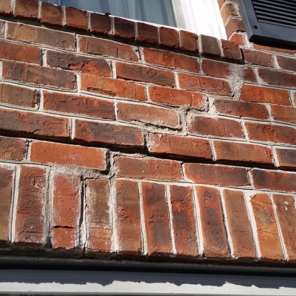 Brick wall with cracks from storm-related soil washout; natural disasters requiring foundation solutions in Jacksonville, FL.