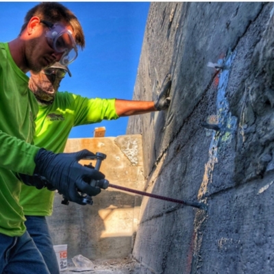 Technician injecting polyurethane grout to stabilize soil and repair seawall erosion behind waterfront property in Palatka, FL.