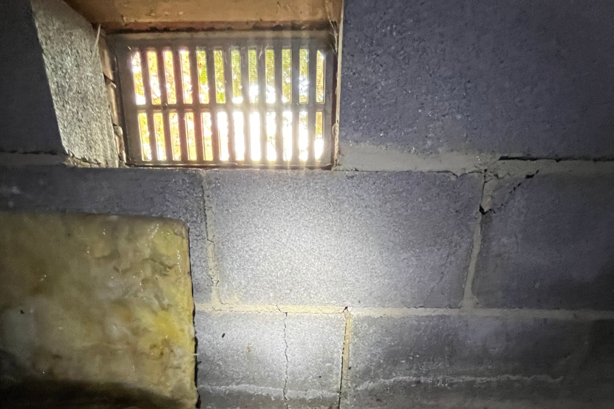 Open crawl space vent letting humid outdoor air enter the block wall area, contributing to damaged floor joist in Ocala, FL.