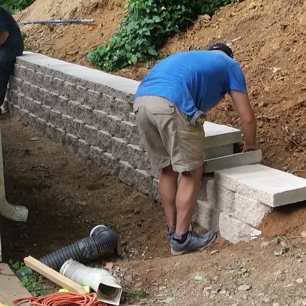 Crew installing a block retaining wall to support shifting soil and prevent slope failure around a property in St. Johns, FL.