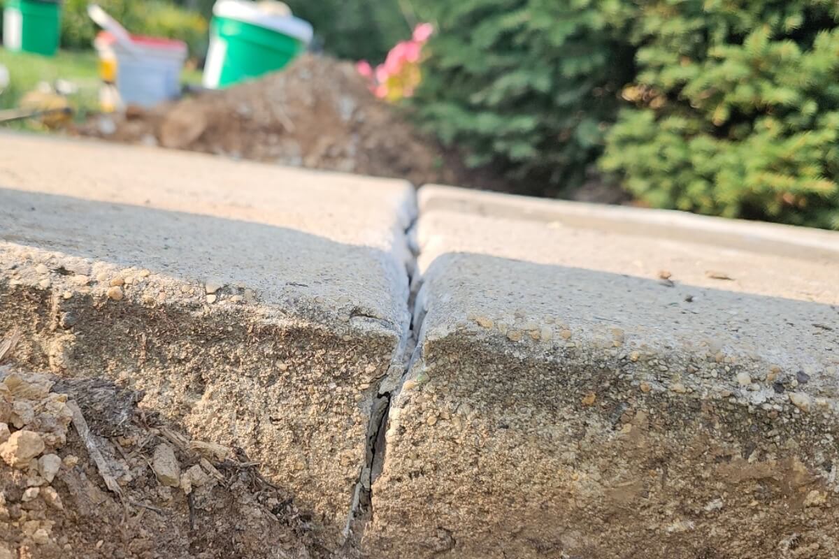 Close-up of a deep, widened crack of concrete walkways, a sign of tree roots lifting concrete in Palm Coast, FL.