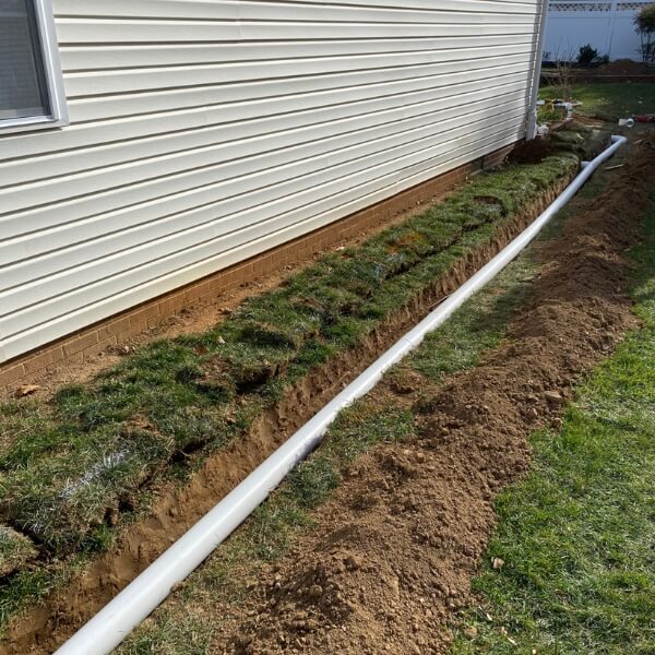 Installed French drain redirecting stormwater away from a concrete slab to prevent soil washout in Fort Lauderdale, FL.