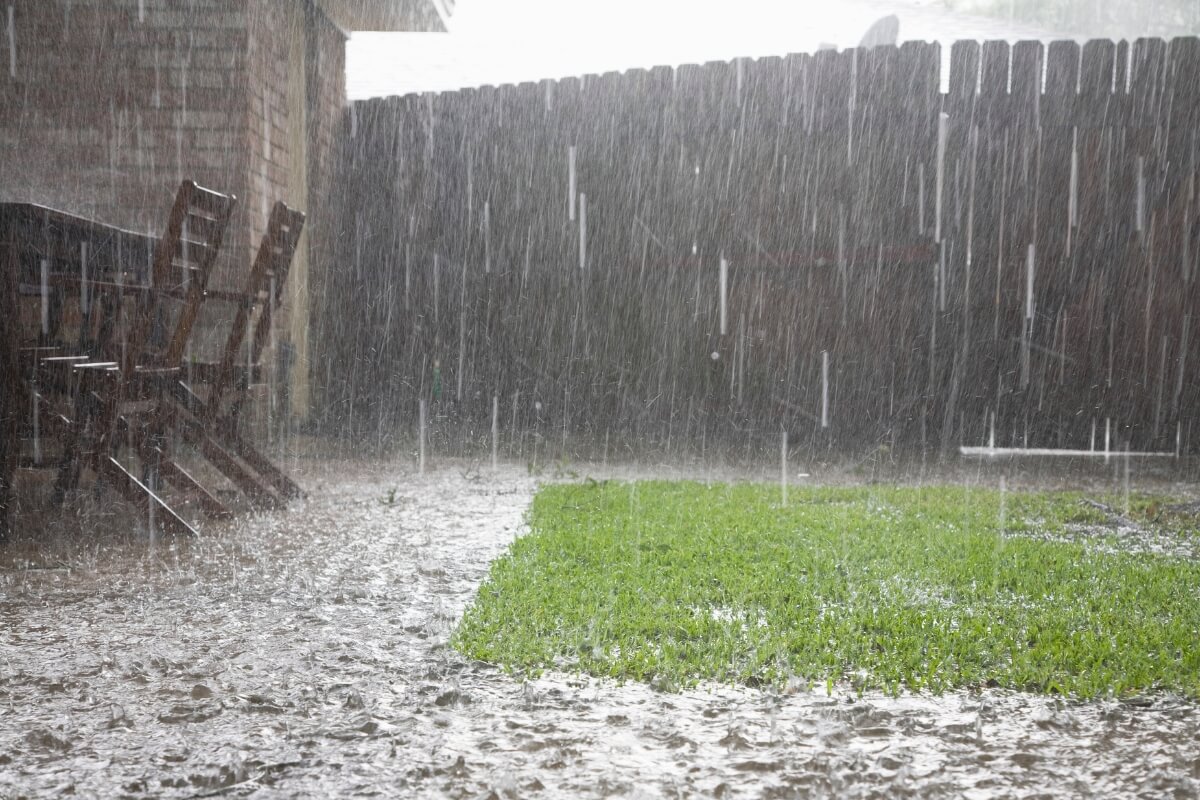 Heavy rain flooding a yard and pooling near concrete surfaces, showing how storms cause concrete water damage in St. Augustine, FL.