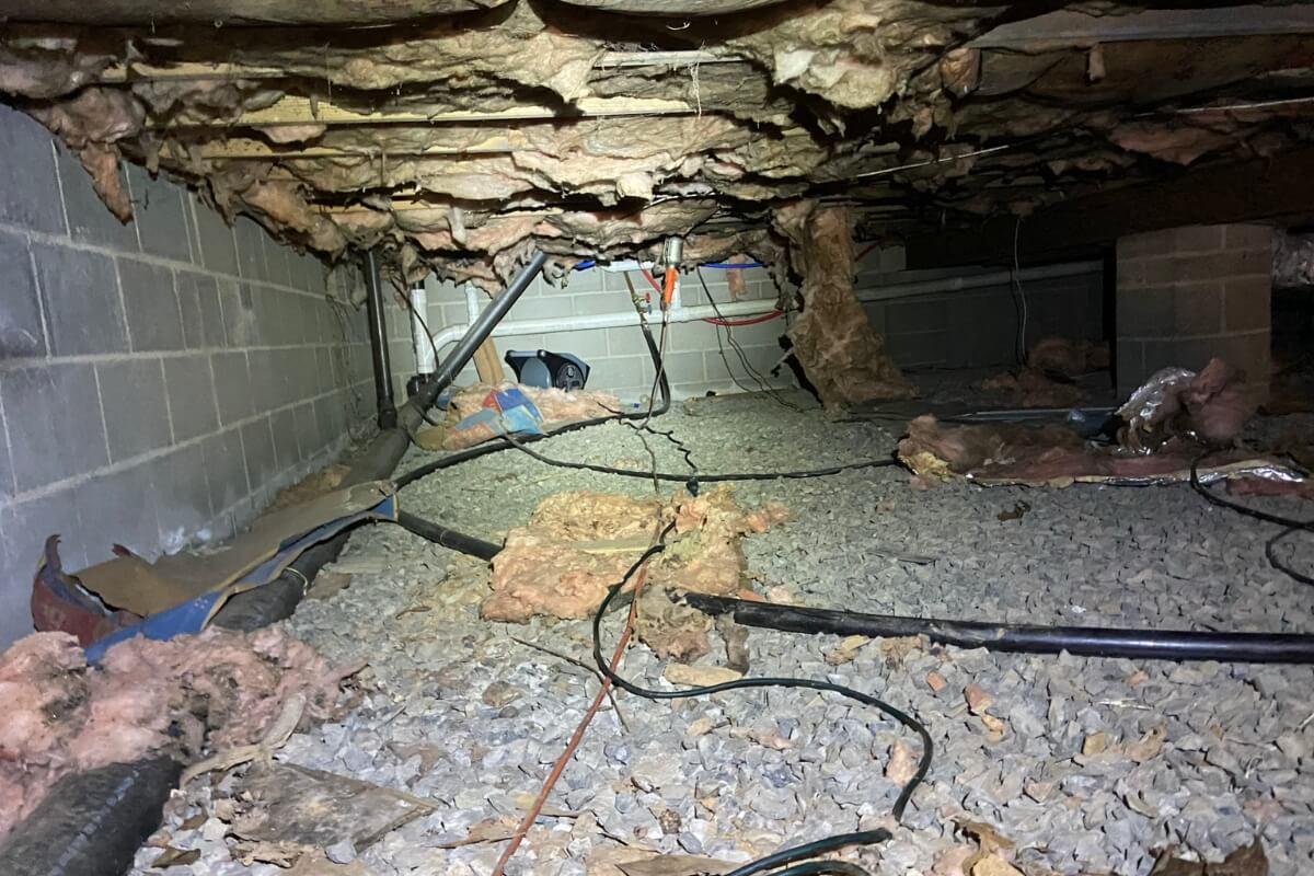 Old deteriorated insulation hanging from crawl space joists, showing aging materials causing fallen insulation in St Johns, FL.