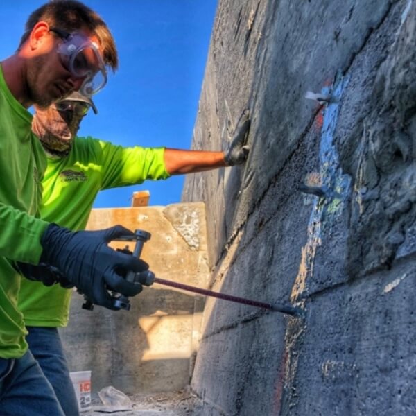 Technician injecting hydrophobic polyurethane grout in a seawall to fill voids from heavy rain and flooding in Middleburg, FL.