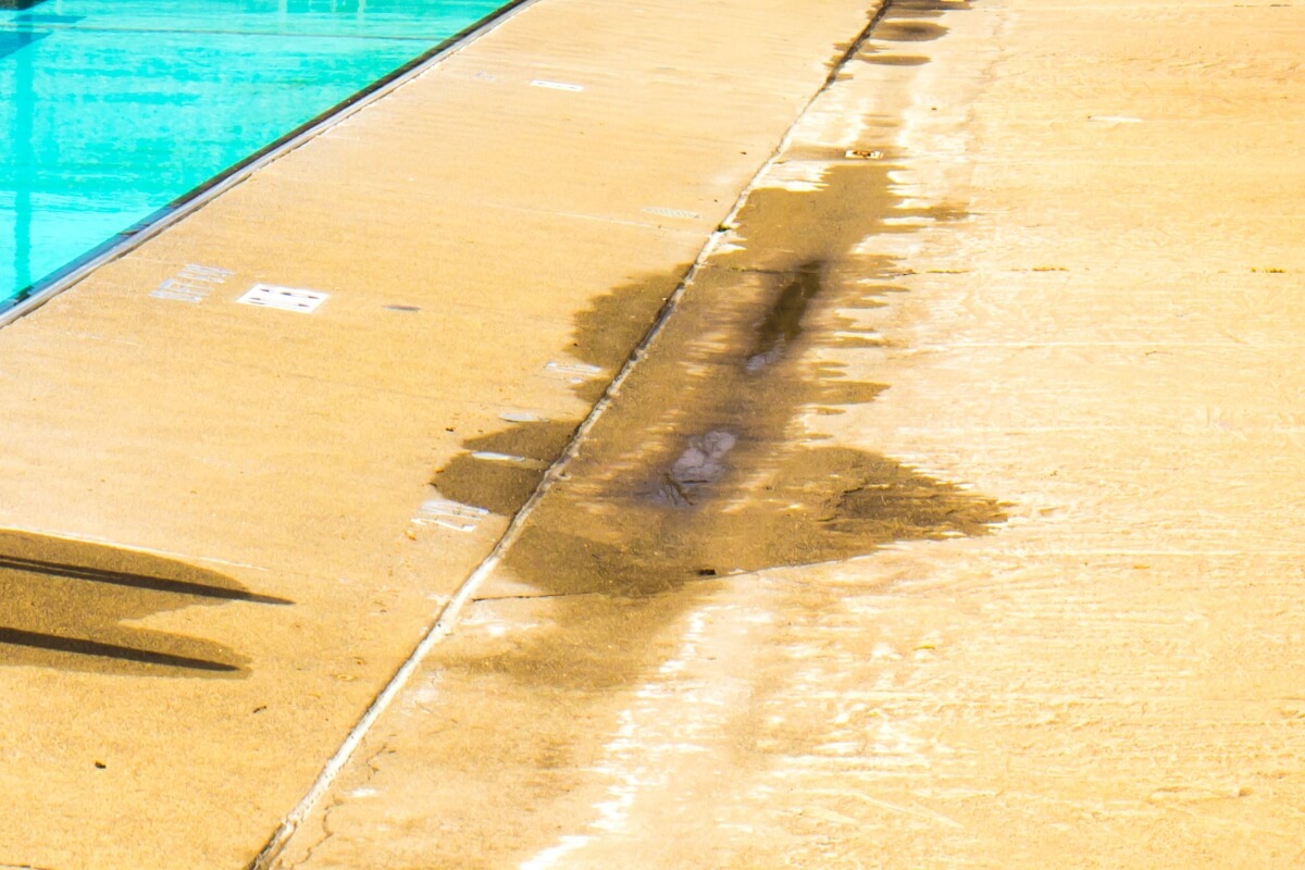 Concrete pool deck surface peeling and fading from repeated chlorine, causes of concrete chemical damage in Palm Coast, FL.