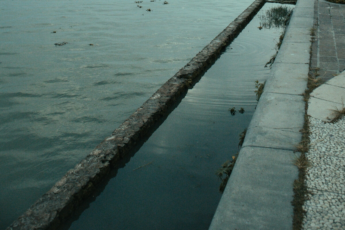 Standing water trapped behind a seawall due to poor drainage, contributing to soil erosion behind seawalls in Palm Coast, FL.