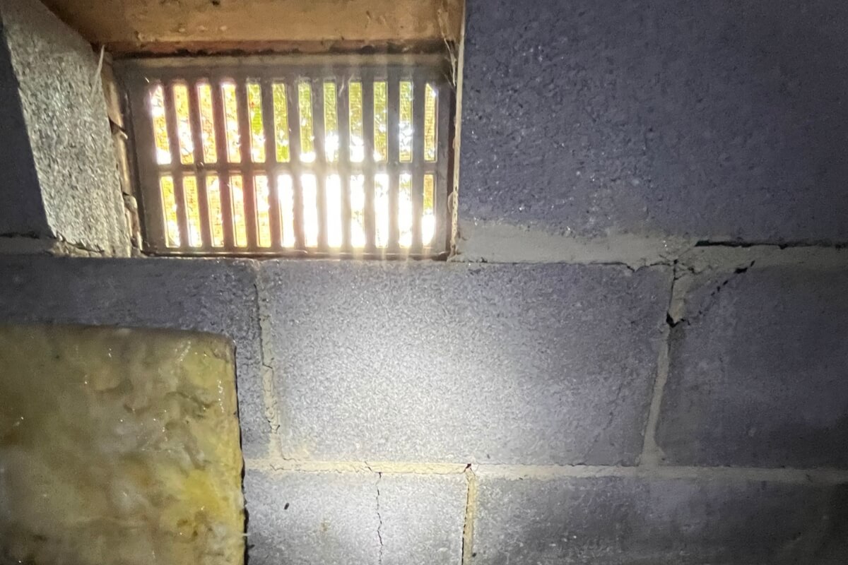 Open crawl space vent letting humid air inside, leading to falling insulation in Ocala, FL.