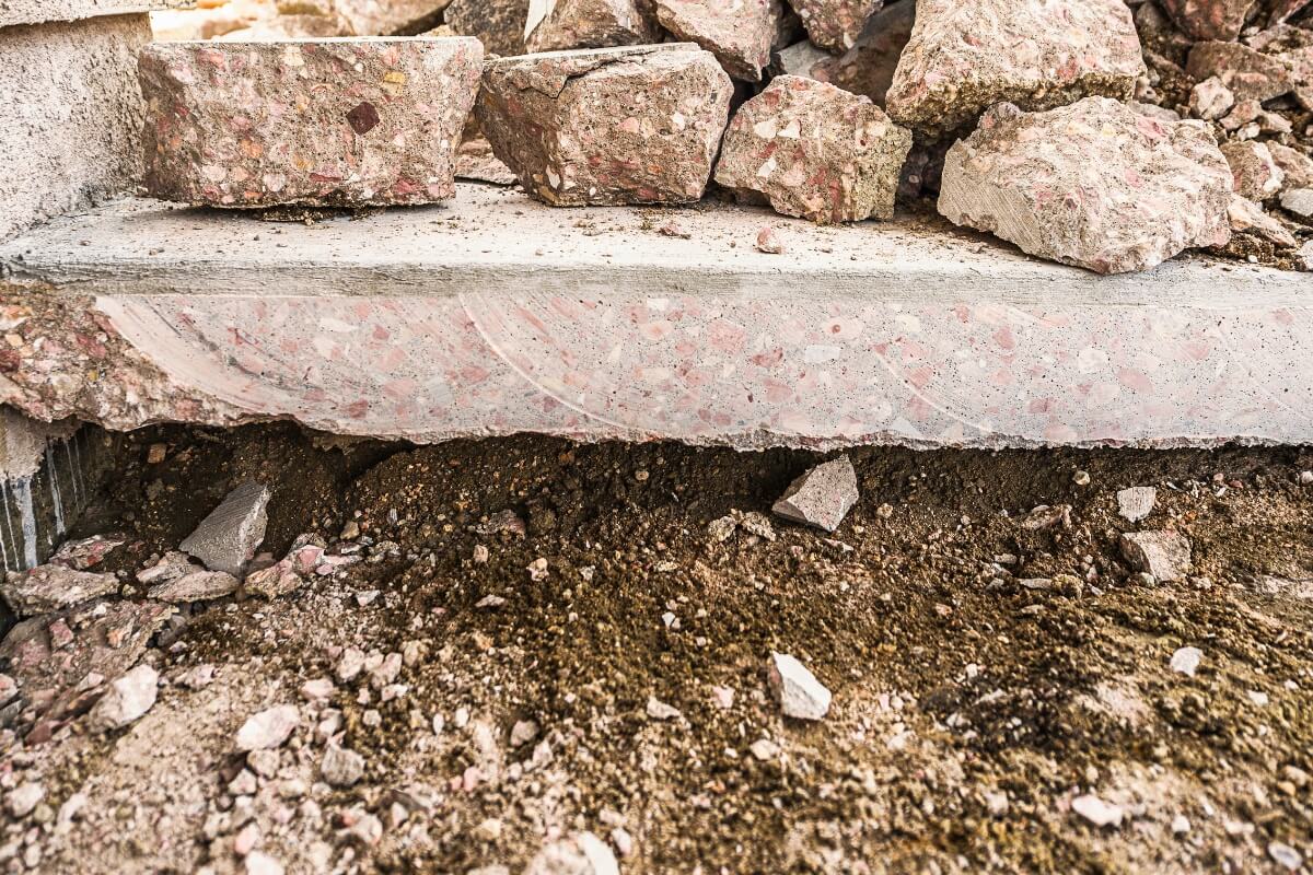 Loose sandy soil shifting away beneath concrete after rainfall, creating erosion pockets in Palm Coast, FL.