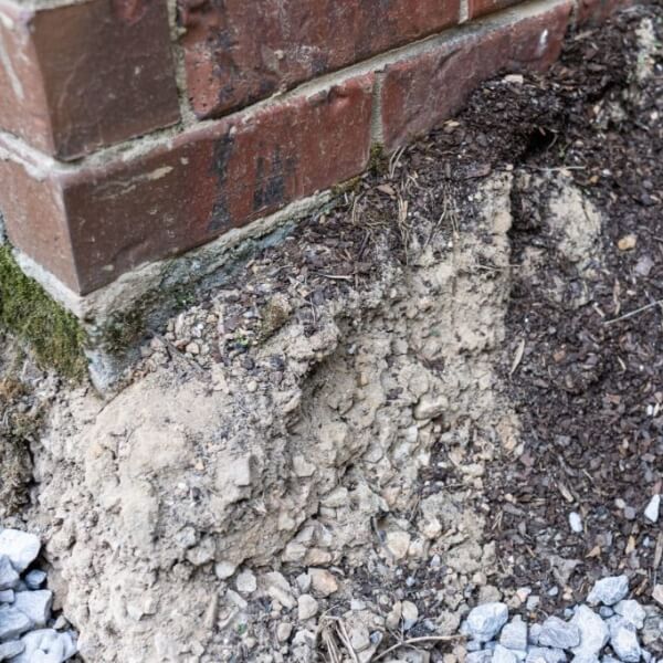 Eroded soil pocket under a cracked concrete slab showing concrete damage, which needs soil washout repair in Jacksonville, FL.