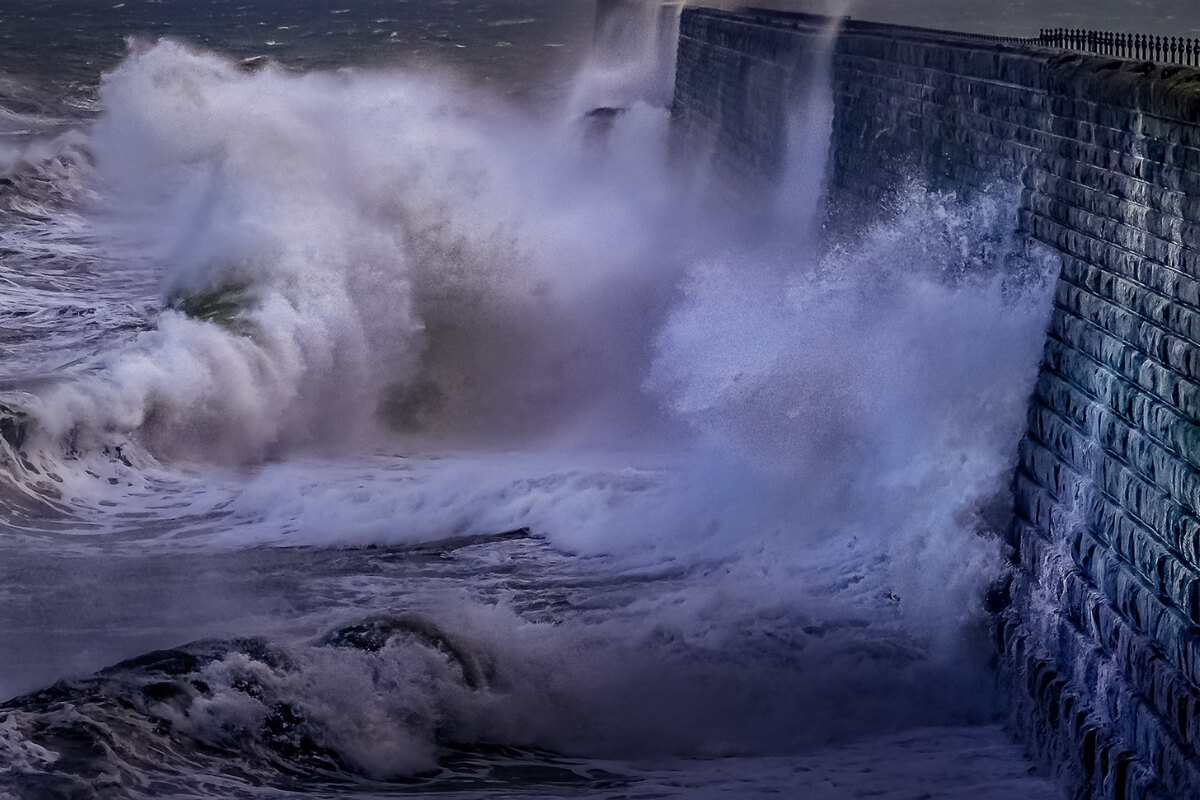 Strong storm surge waves hitting a seawall, increasing erosion and soil displacement, cause seawall damage in Gainesville, FL.