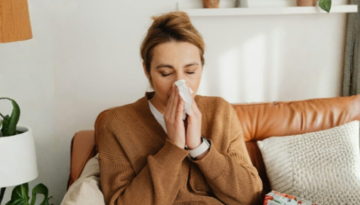 A person sneezing, showing allergy or asthma symptoms in Gainesville, FL, a sign of a crawl space problem.