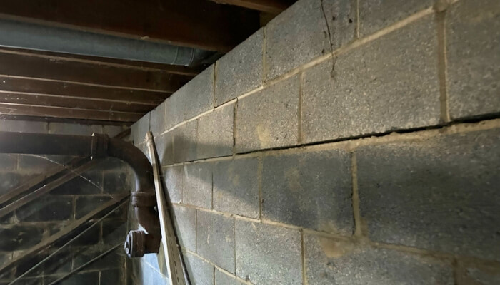 Bowing basement wall in Ocala, FL, showing pressure from saturated soil and moisture buildup around the foundation.