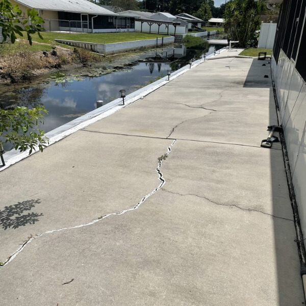 Cracked concrete seawall walkway due to erosion and water pressure, causing seawall damage in St. Augustine, FL, waterfront.