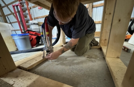 Technician injecting polyurethane foam beneath a settled slab to level and stabilize for expert concrete lifting in Lake City, FL.