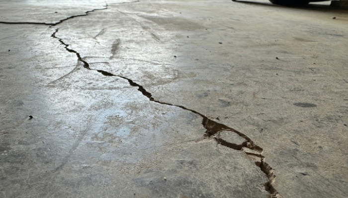 Cracked garage floor in Ocala, FL, showing concrete stress caused by moisture movement beneath the slab.