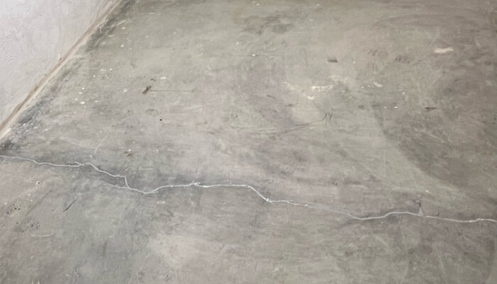 Cracks forming across a basement floor in Ocala, FL, indicating possible foundation stress in the home.