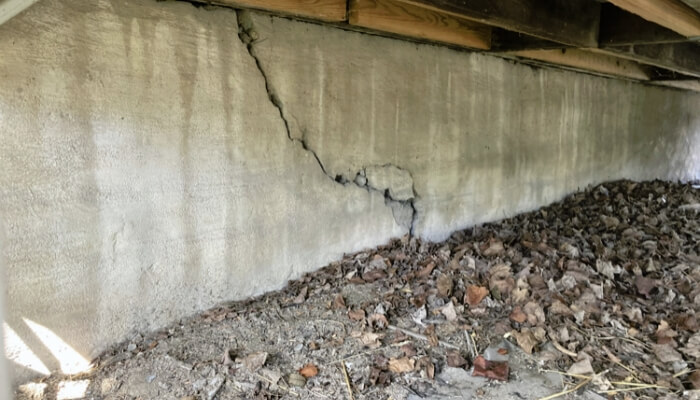 Cracks in a crawl space foundation wall of a Lake City, FL home, indicating structural stress from soil and moisture conditions.
