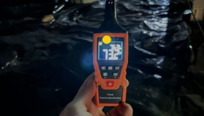 Handheld humidity meter reading high moisture levels inside a Gainesville crawl space, indicating excess humidity.