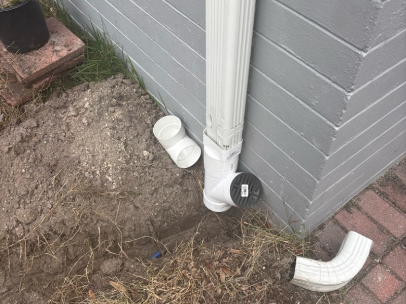 Downspout PVC fittings connect to the gutter to route roof runoff into underground pipe for downspout extension in Orange Park, FL.