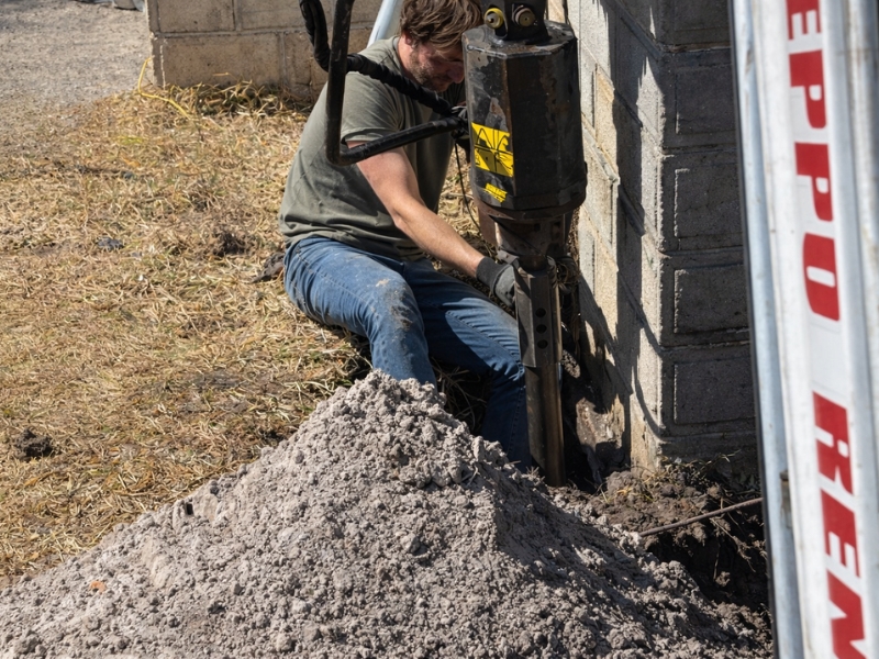 Technician operating hydraulic equipment to lift and stabilize the settling front porch foundation in St. Augustine, FL.