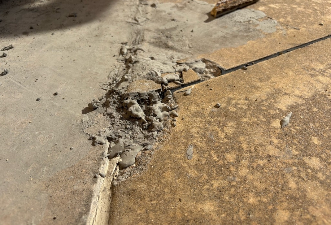 Close-up of damaged concrete topping slab and exposed joint failure caused by waterproofing system failure in Fernandina Beach, FL.