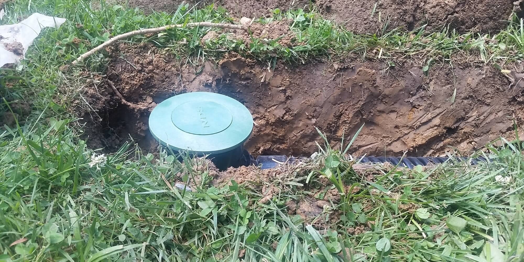 A pop-up emitter discharge point was installed for a buried downspout drainage system in a Florida yard to redirect rainwater.