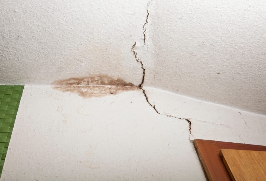 Ceiling crack running from wall junction with visible water staining in a Florida home showing moisture damage and structural movement.