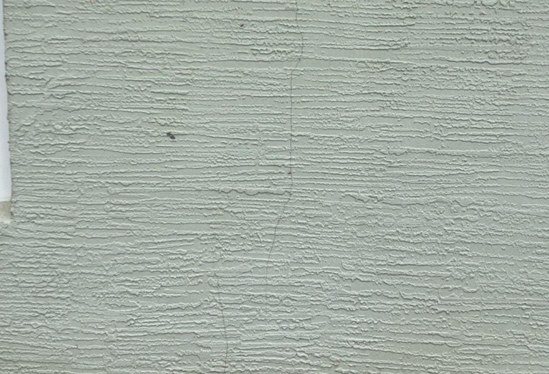 Close-up of vertical crack running full height of exterior stucco wall from foundation settlement in Palm Coast, FL.