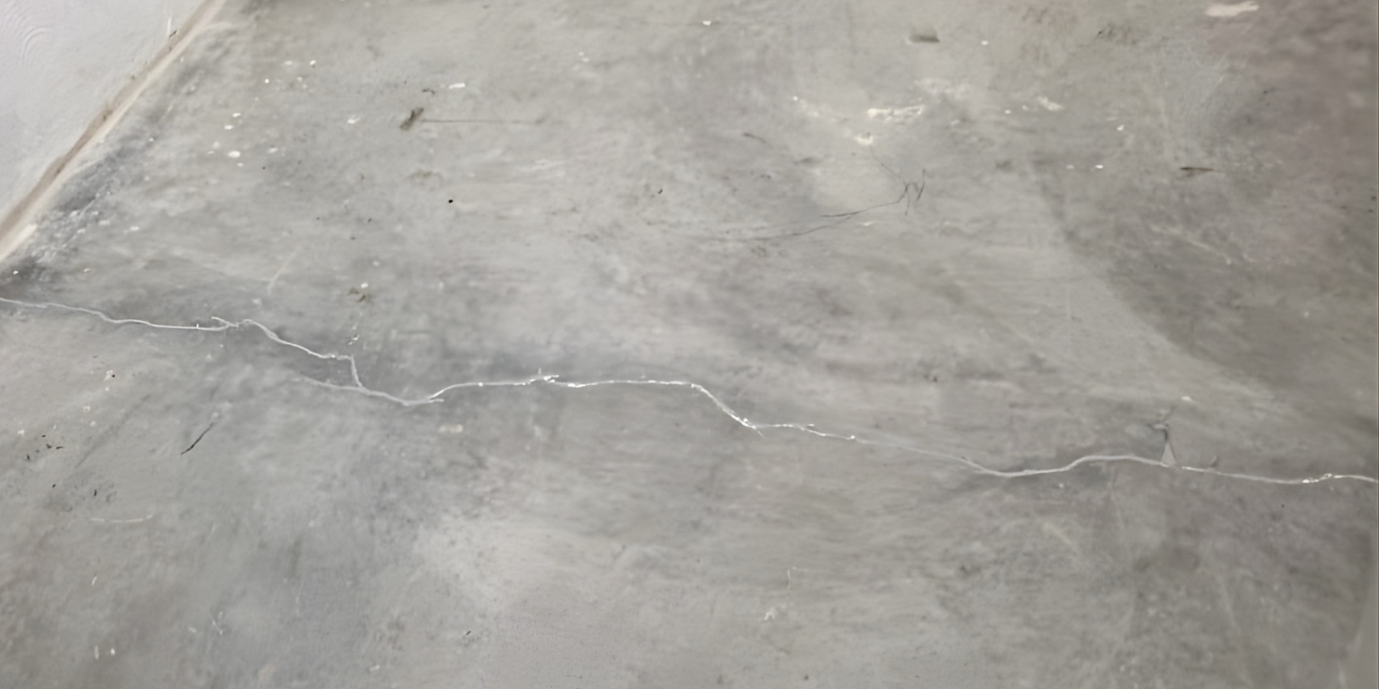 Close-up of a hairline crack on a concrete slab surface in a home driveway in Northern Florida.