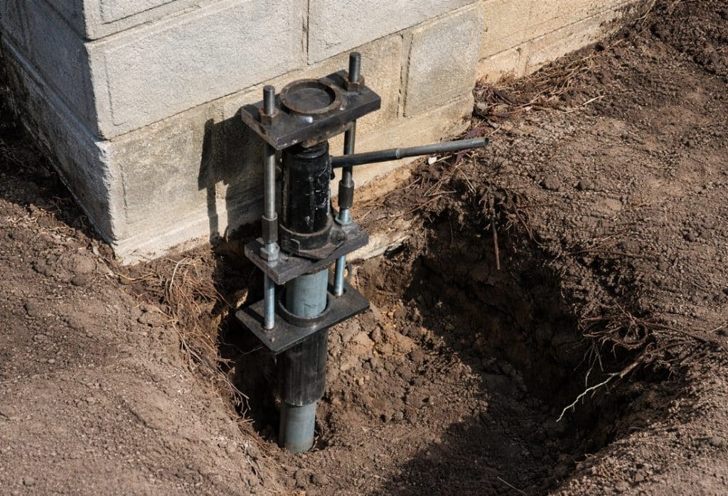 Push pier installed to stabilize and lift a foundation damaged by expansive soil movement in Gainesville, FL.