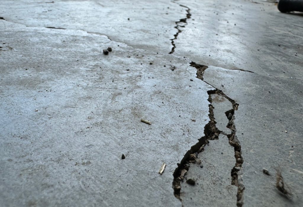 Structural crack on a concrete slab in Gainesville, FL, showing a width greater than 1/8 inch, and where one side sits higher.