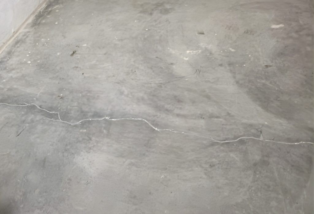Thin hairline crack in a concrete slab surface, showing width and shallow depth of a non-structural crack in Jacksonville, FL.