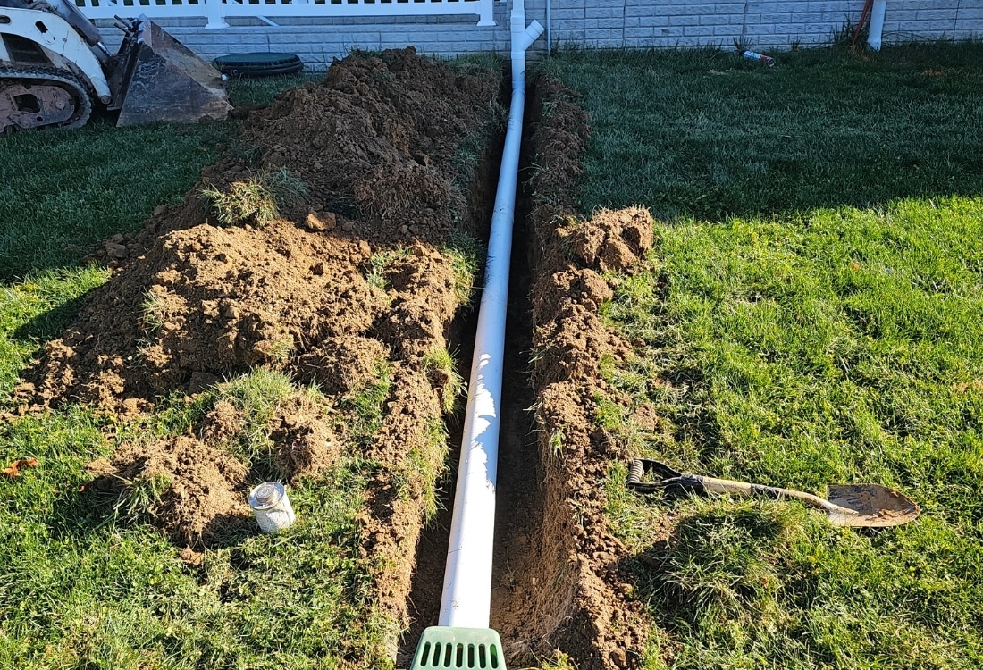 PVC pipe laid in a trench during buried downspout drainage installation in St Augustine, FL.
