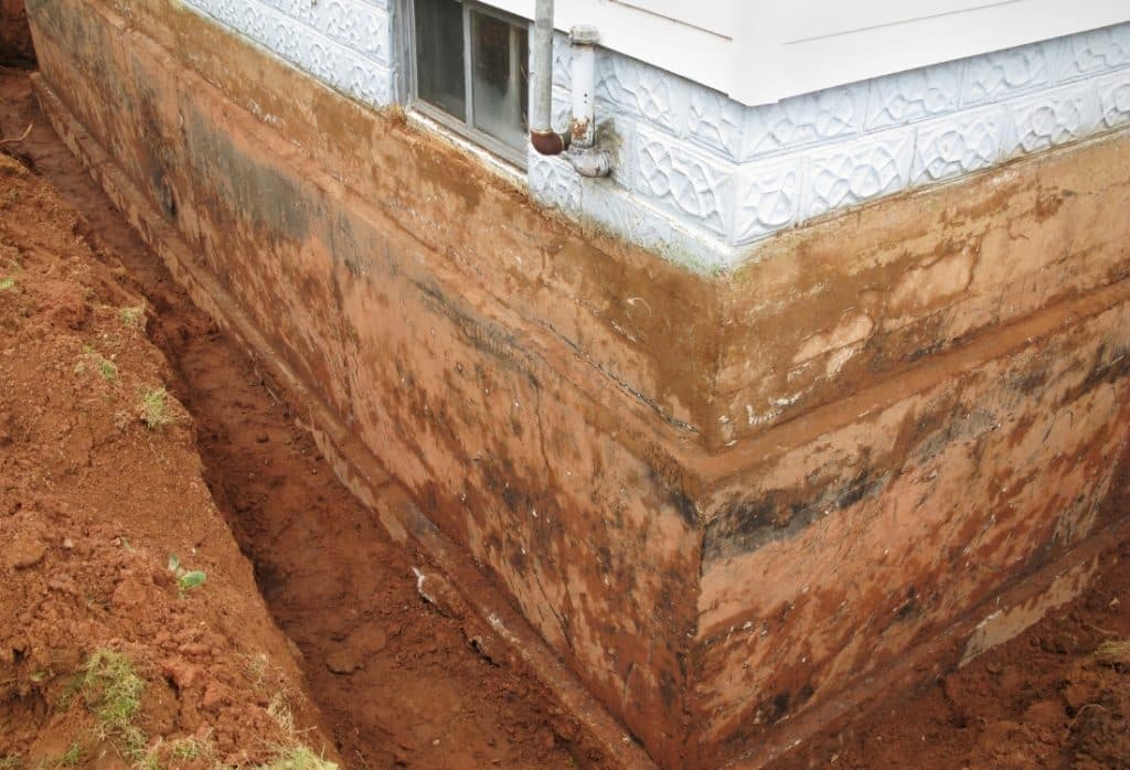 Excavated foundation wall with backfilled soil layers where clay bow effect will happen causing foundation leaks in St Augustine, FL.