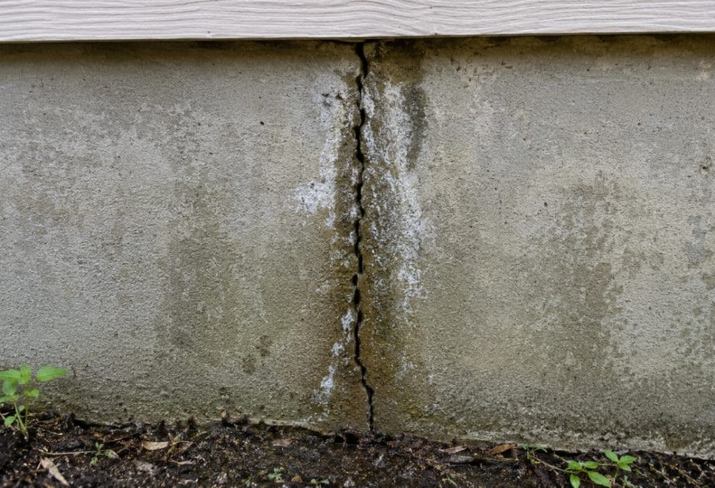 Vertical crack with efflorescence and water staining on a concrete foundation wall causing foundation leaks in Gainesville, FL.