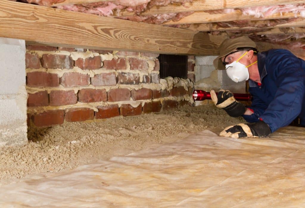 Foundation inspector examining a crawl space brick wall for crawl space assessment during foundation inspection in Gainesville, FL.